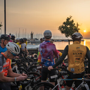 ciclisti in attesa dello start con lo sfondo del lago all'alba