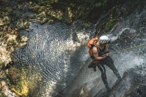 ragazzo si cala da una cascata di un torrente facendo canyoning
