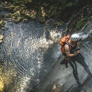 ragazzo si cala da una cascata di un torrente facendo canyoning