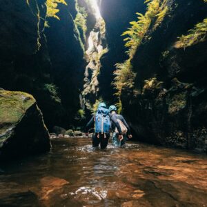 due ragazzi camminano tra le rocce di un torrente facendo canyoning